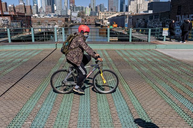 A person rides a bike over a bridge across the Gowanus canal.